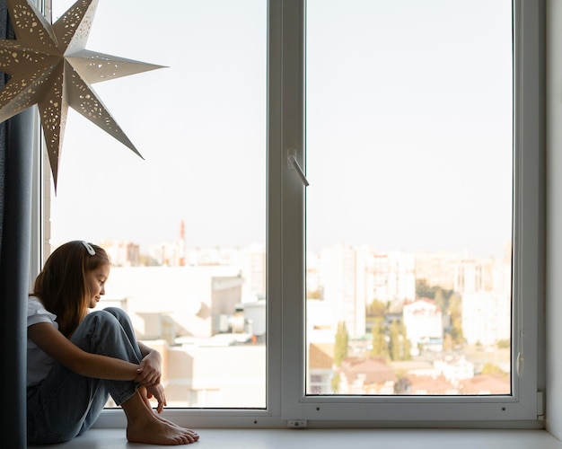 Photo gratuite vue latérale fille regardant par la fenêtre