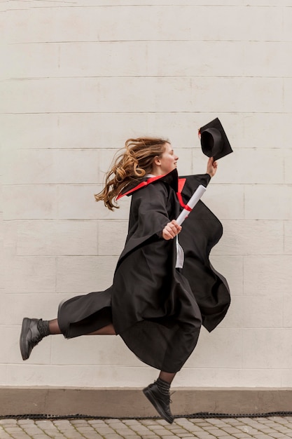 Vue latérale fille sautant à l'obtention du diplôme