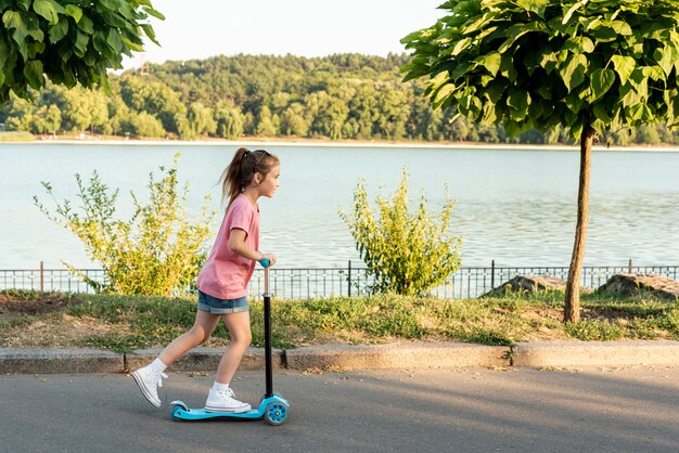 Vue latérale d'une fille sur un scooter bleu