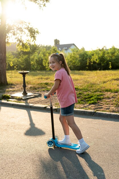 Vue latérale d'une fille sur un scooter bleu