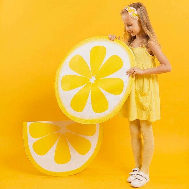 Photo gratuite vue latérale d'une fille tenant une décoration de tranche de citron