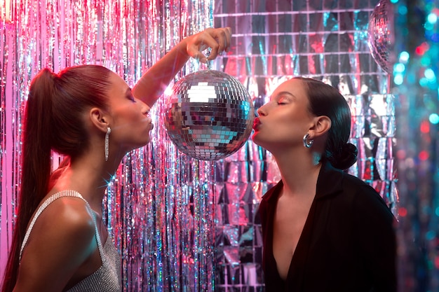 Photo gratuite vue latérale filles embrassant une boule disco