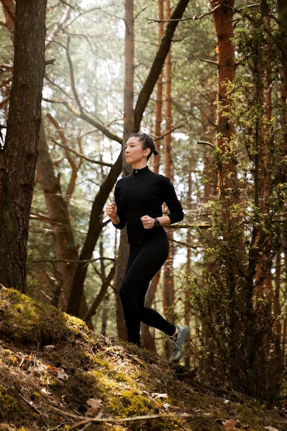 Vue latérale fit femme qui court dans la nature