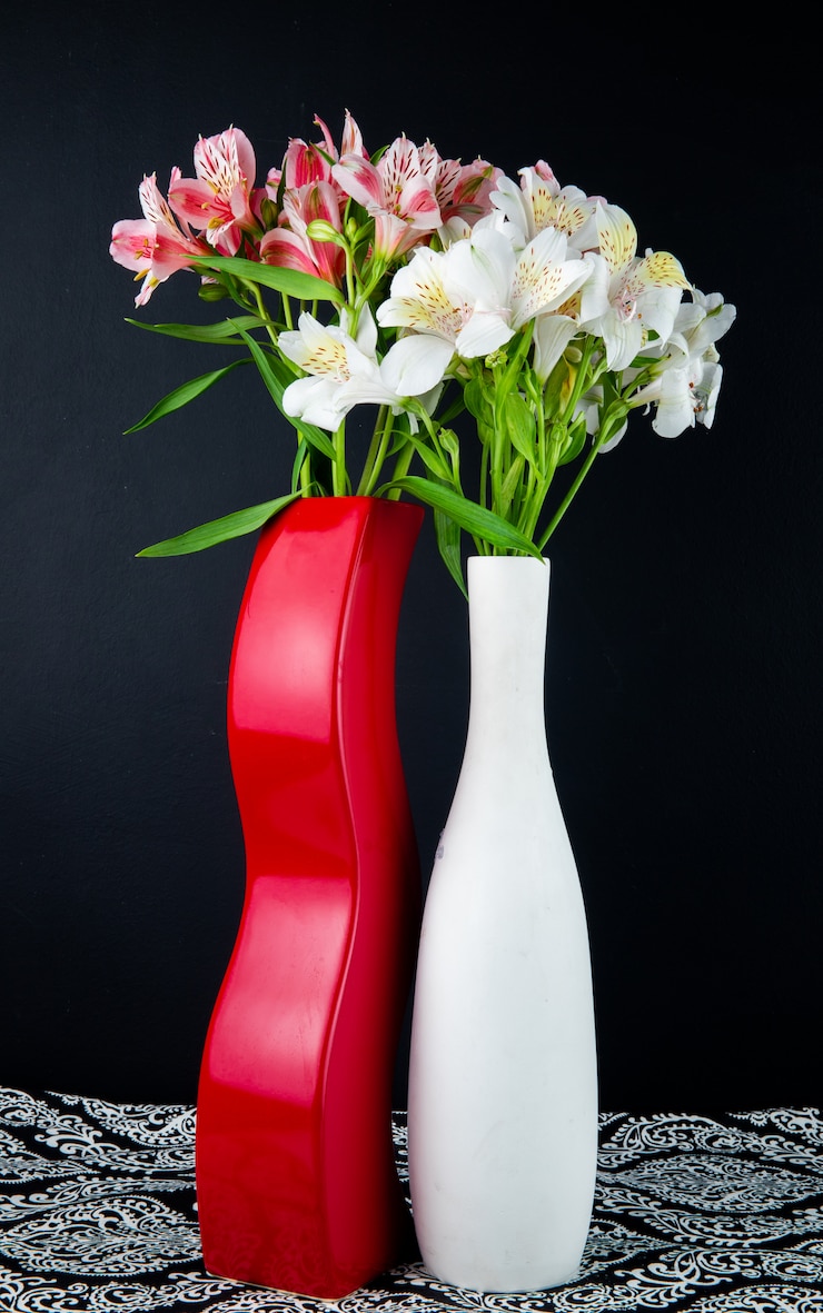 Photo gratuit vue latérale des fleurs d'alstroemeria de couleur blanche et rose dans des vases blancs et rouges sur fond noir