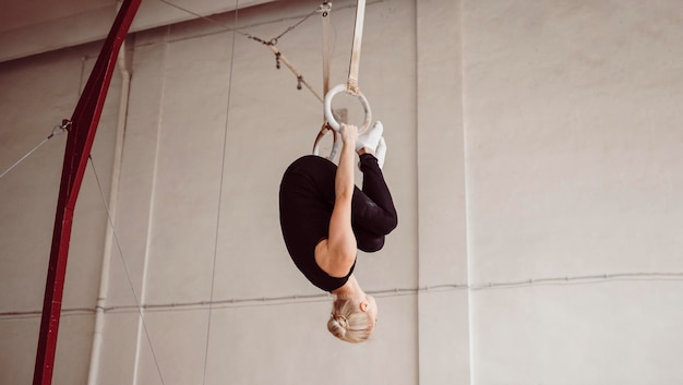 Vue latérale de la formation de femme athlétique sur les anneaux de gymnastique