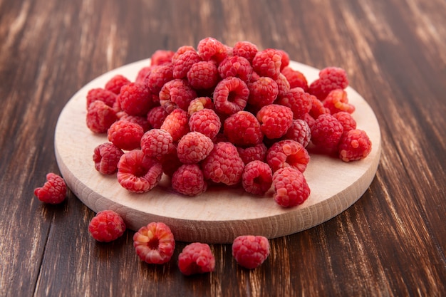 Vue latérale des framboises sur une planche à découper et sur bois