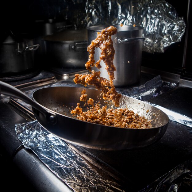 Vue latérale frite hachée avec poêle et papier d'aluminium dans le poêle