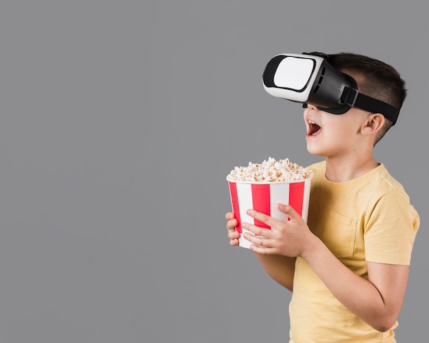 Vue Latérale D'un Garçon Heureux Tenant Du Pop-corn Et Portant Un Casque De Réalité Virtuelle