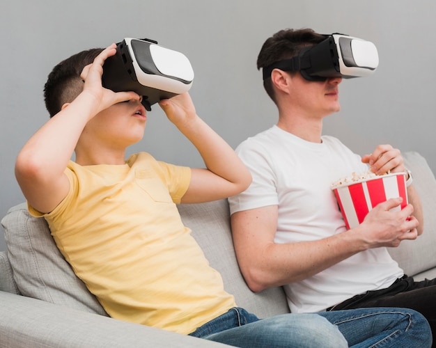 Vue latérale d'un garçon et d'un homme regardant un film à l'aide d'un casque de réalité virtuelle