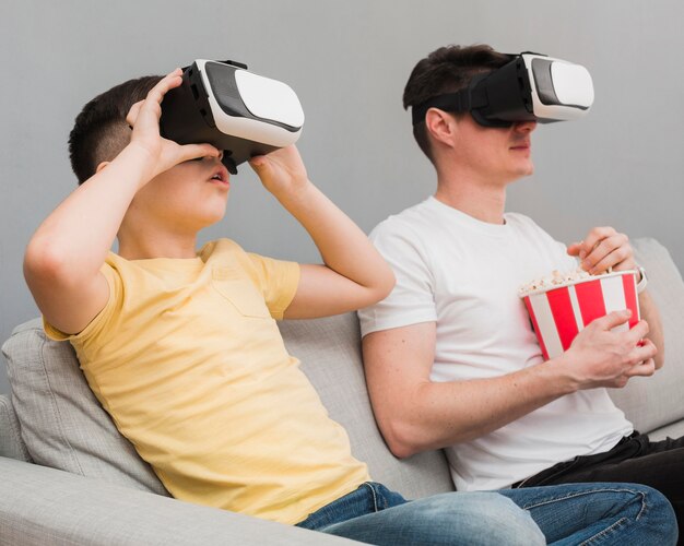 Vue latérale d'un garçon et d'un homme regardant un film à l'aide d'un casque de réalité virtuelle