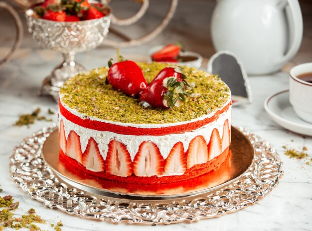 Vue latérale d'un gâteau aux fraises avec des miettes de pistache sur la table