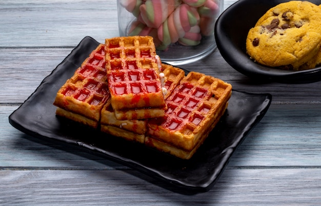 Vue latérale des gaufres au sirop de fraise sur un plateau noir