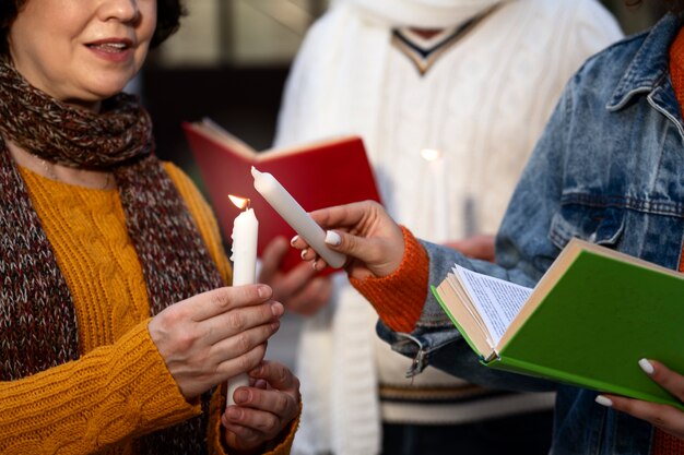 Vue latérale des gens avec des livres et des bougies