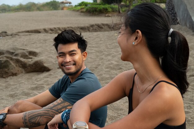 Vue latérale des gens souriants assis sur la plage