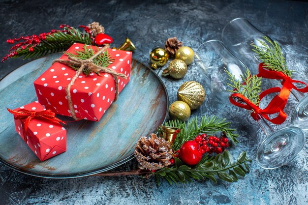 Vue latérale des gobelets en verre avec sur une assiette bleue et des accessoires de décoration de branches de sapin sur fond sombre