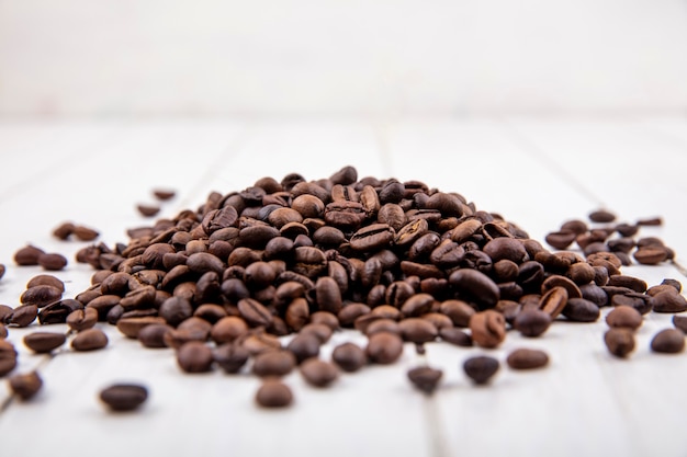 Vue latérale des grains de café frais isolé sur un fond en bois blanc