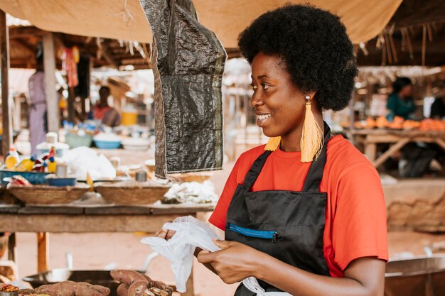 Vue latérale heureuse femme africaine au marché