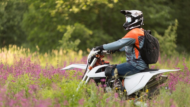 Photo gratuite vue latérale homme actif à moto dans la forêt