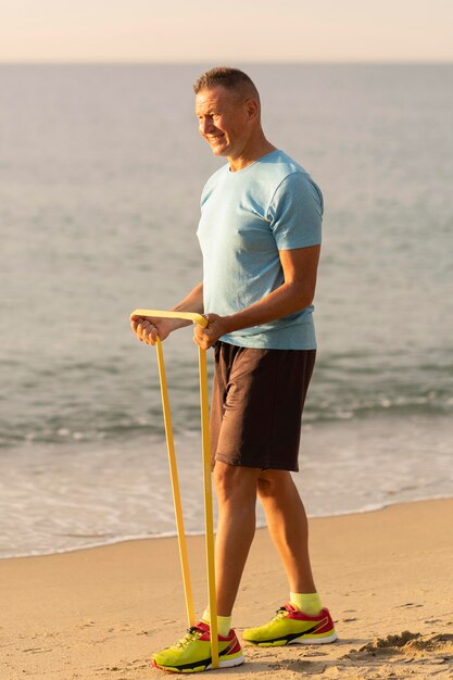 Vue latérale d'un homme âgé avec corde élastique sur la plage