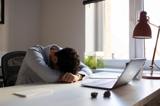 Vue latérale homme anxieux sur le bureau