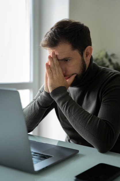 Vue latérale homme anxieux travaillant à la maison