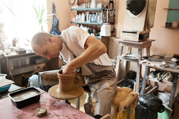 Vue latérale homme argile sculptant à l'intérieur