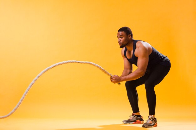 Vue latérale d'un homme athlétique exerçant une corde
