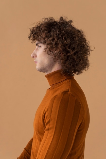 Vue latérale homme aux cheveux bouclés avec chemisier marron posant