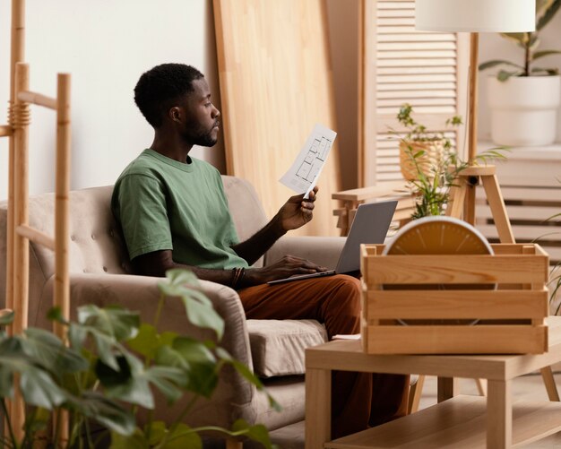 Vue latérale de l'homme sur le canapé faisant un plan pour redécorer la maison