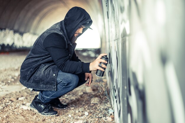 Vue latérale d&#39;un homme à capuche, peinture sur mur de graffitis