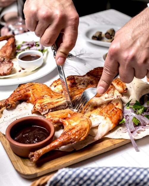 Vue latérale un homme coupe le tabac sur du pain pita avec sauce et oignons