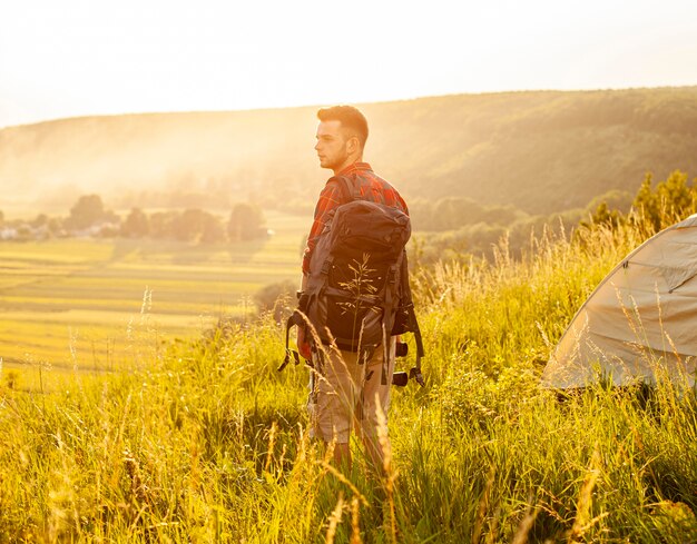 Vue latérale de l'homme dans le champ vert avec sac à dos