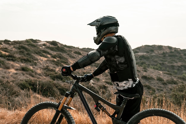 Vue latérale de l'homme dans l'équipement de vélo de montagne