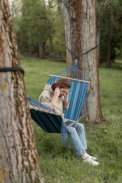 Vue latérale de l'homme dans un hamac dans la nature