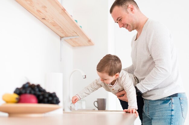 Vue latérale de l'homme avec l'enfant dans la cuisine