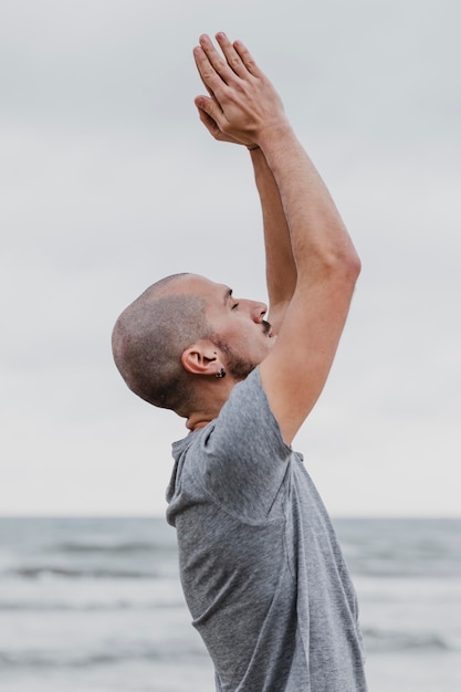 Vue latérale de l'homme faisant du yoga et levant les bras à l'extérieur