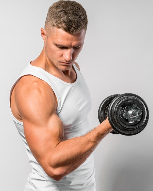 Vue latérale de l'homme en forme avec débardeur travaillant avec poids