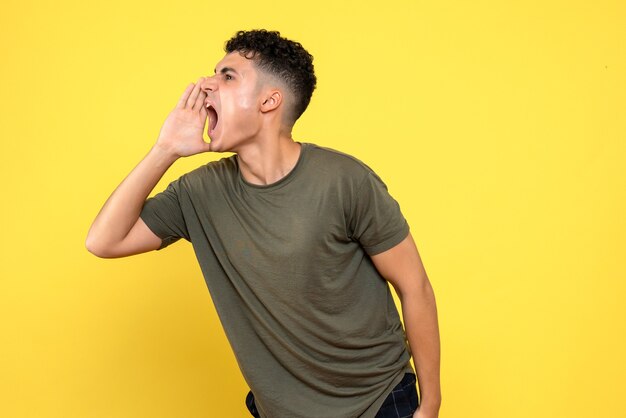 Vue latérale de l'homme l'homme souriant tient ses mains près de son visage et crie vers la droite