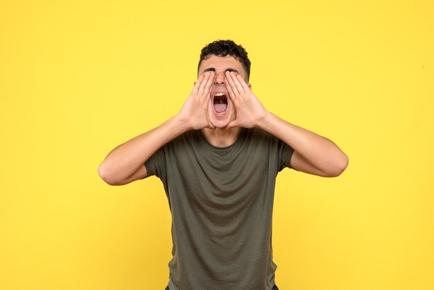 Vue latérale de l'homme l'homme souriant tient ses mains près de son visage et hurle