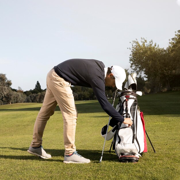 Vue latérale de l'homme jouant au golf sur le terrain