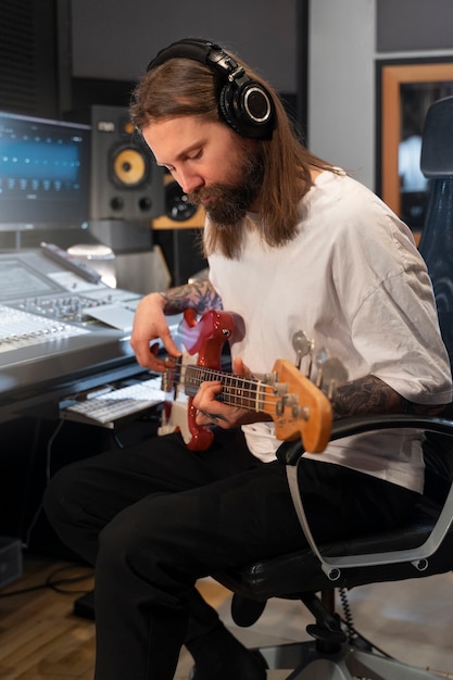 Vue latérale homme jouant de la guitare en studio