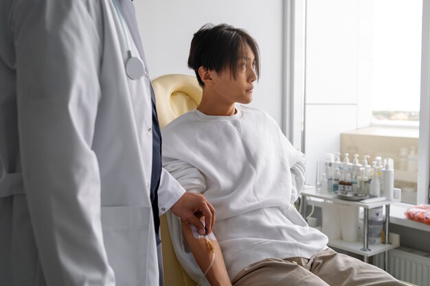 Vue latérale homme malade assis sur une chaise