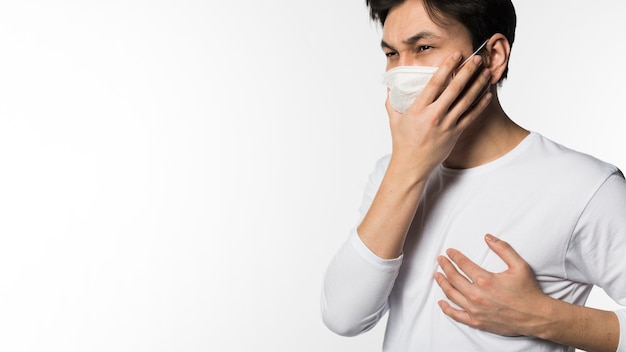 Vue latérale de l'homme avec un masque médical touchant sa poitrine