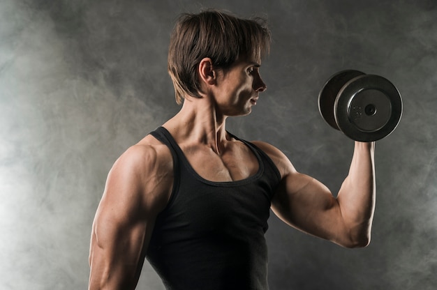 Vue latérale d'un homme musclé tenant un poids