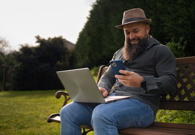 Vue latérale homme avec ordinateur portable à l'extérieur