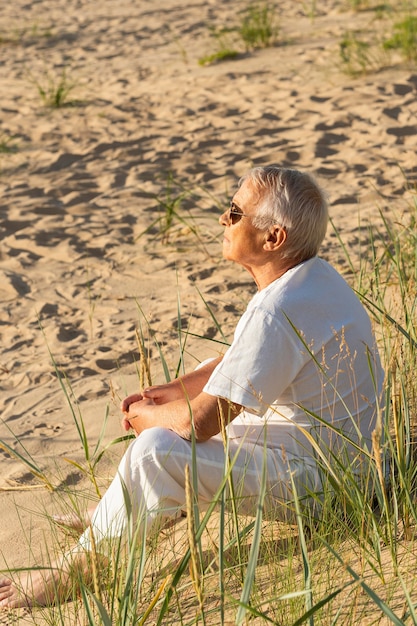 Photo gratuite vue latérale d'un homme plus âgé se reposant au soleil sur la plage