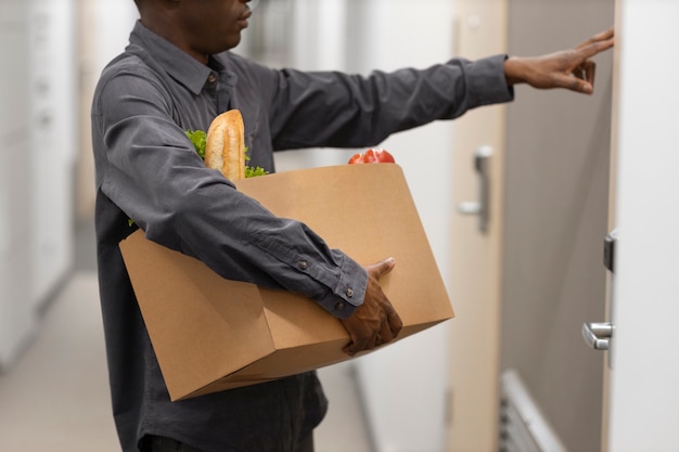 Photo gratuite vue latérale homme portant une boîte d'épicerie
