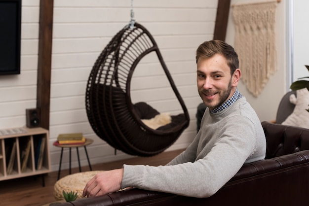 Vue latérale d'un homme posant sur un canapé à la maison