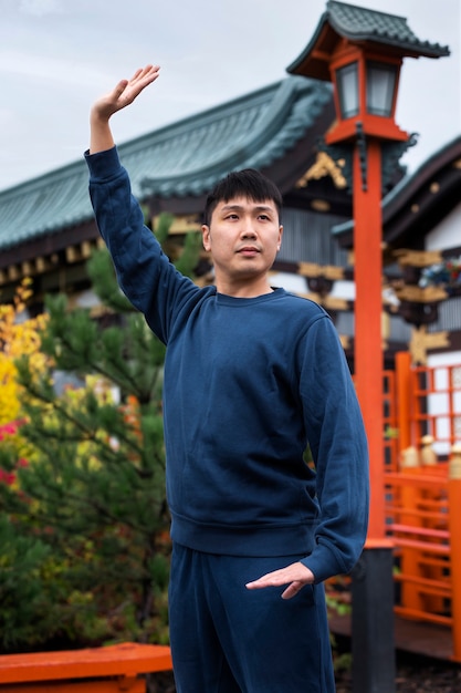 Vue latérale homme pratiquant le tai chi à l'extérieur