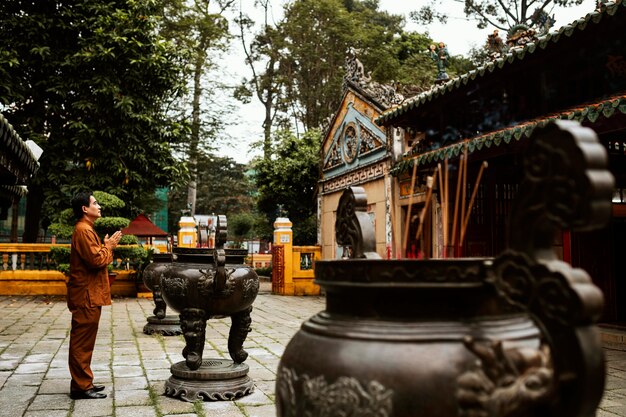 Vue latérale de l'homme priant au temple avec de l'encens